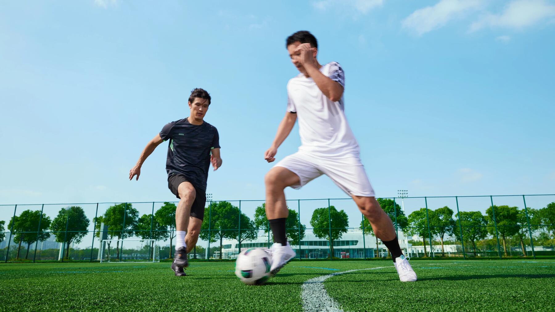 Zwei Fußballspieler aus gegnerischen Teams spielen auf einem markierten Spielfeld gegeneinander