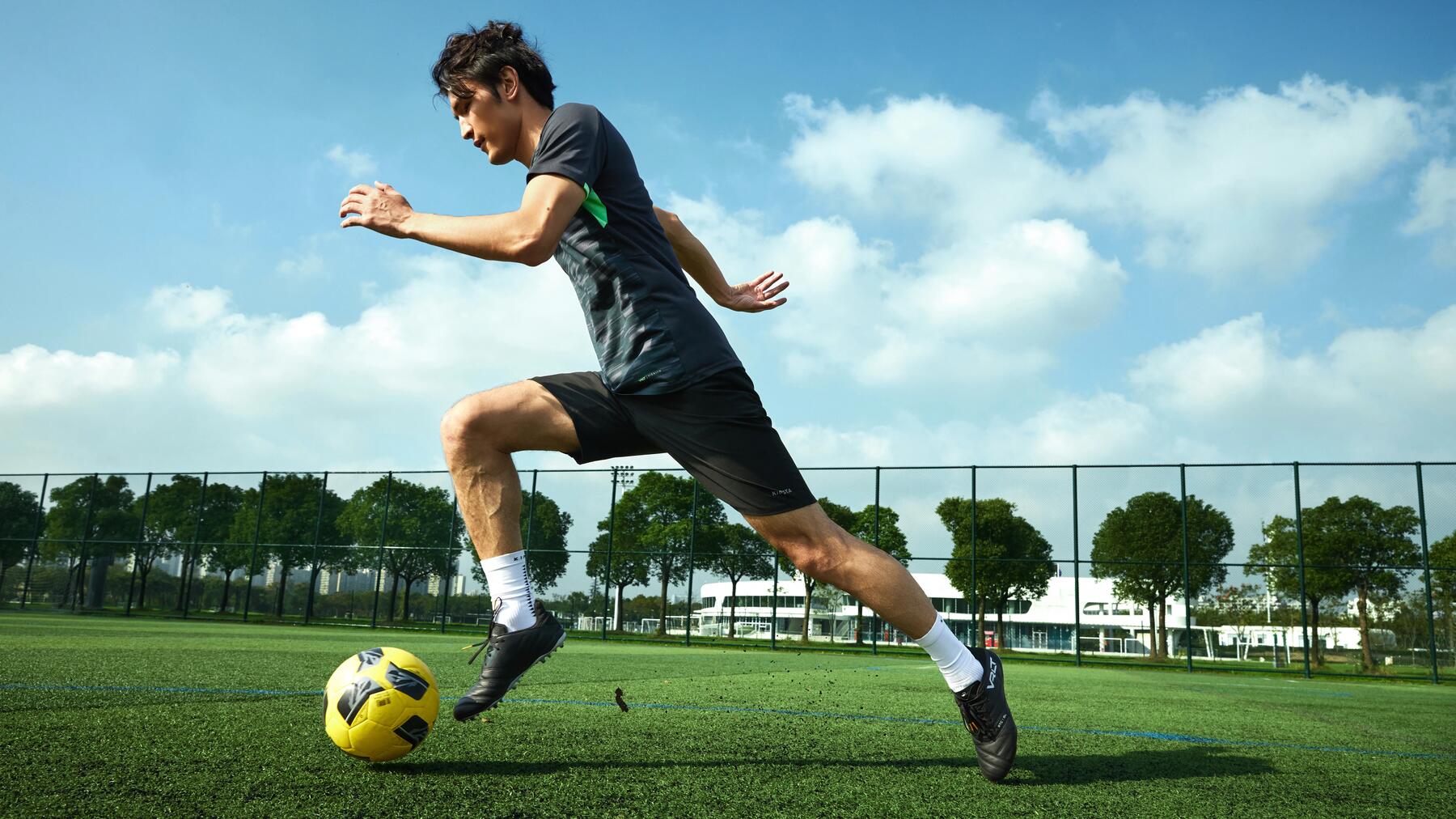 Persoon die rent met een voetbal op het voetbalveld.