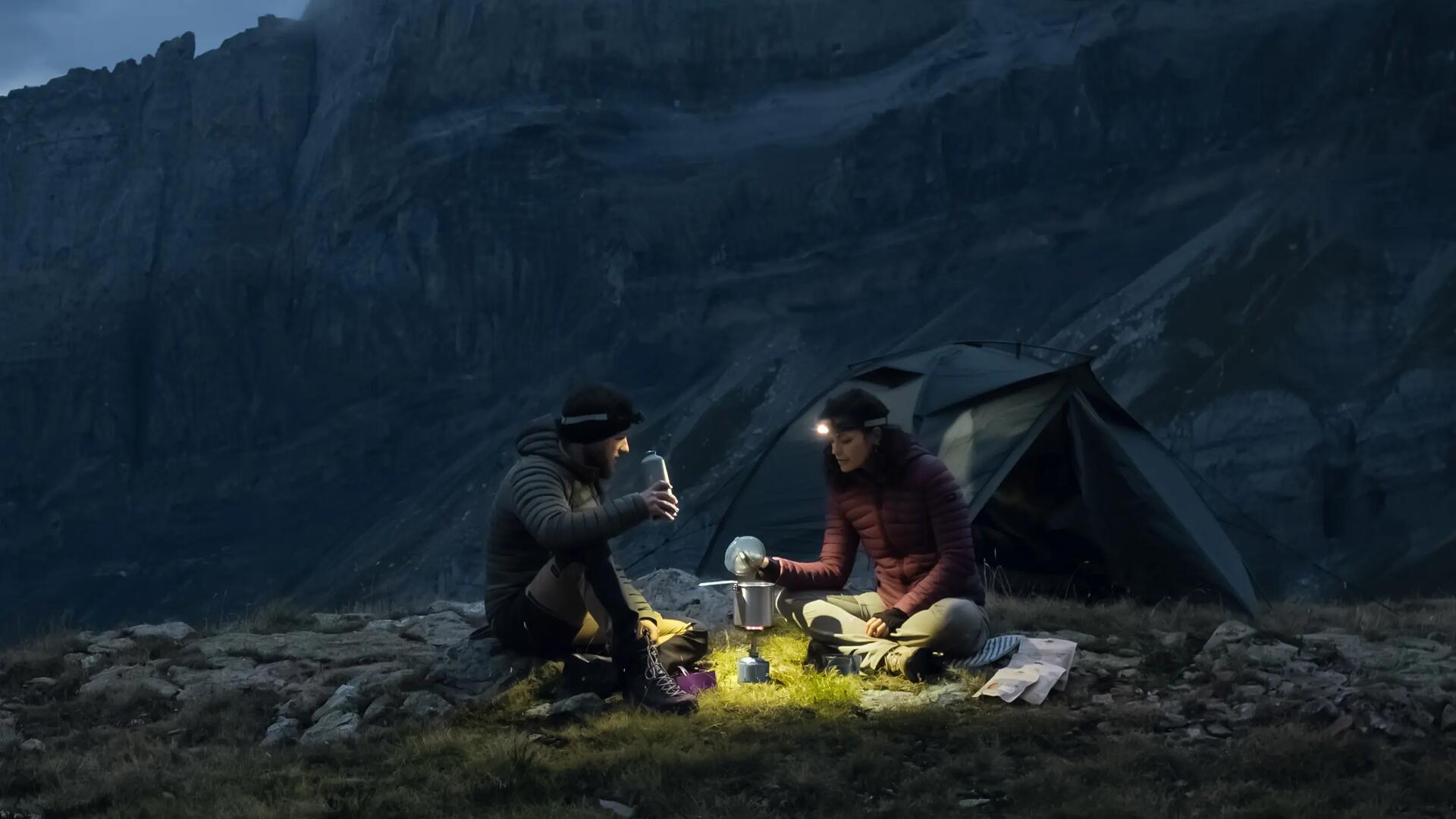Para alpinistów podgrzewająca na palniku w menażce jedzenie nocą