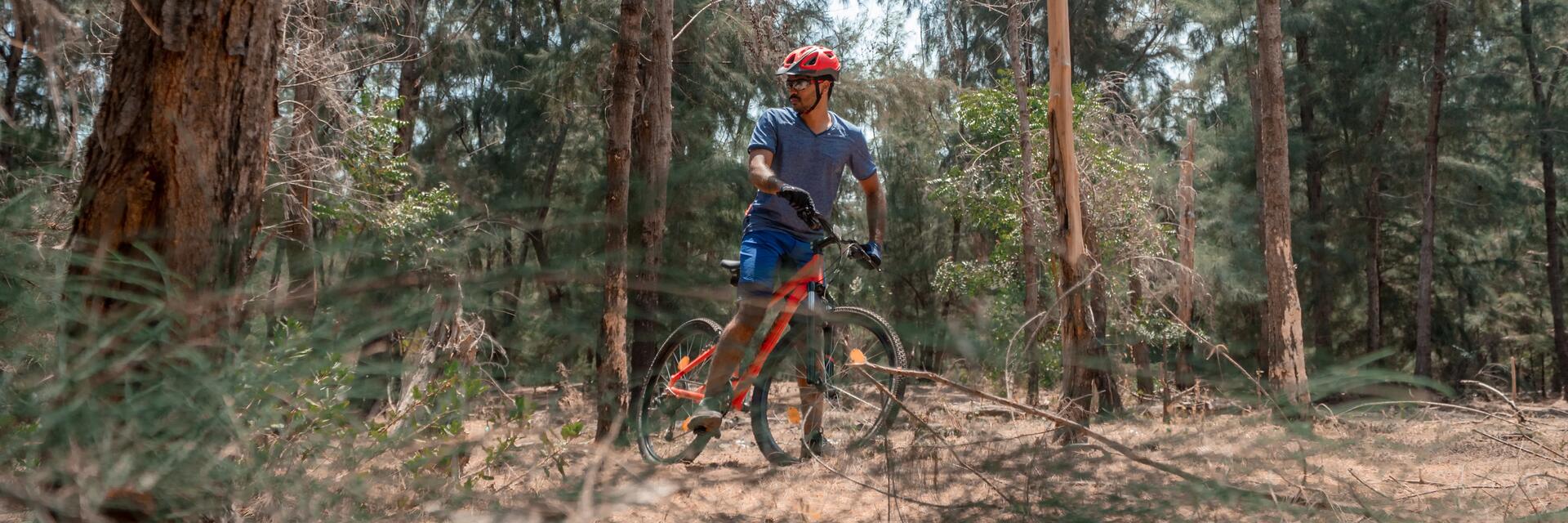 Mężczyzna w kasku i odzieży rowerowej jadący na rowerze MTB po lesie