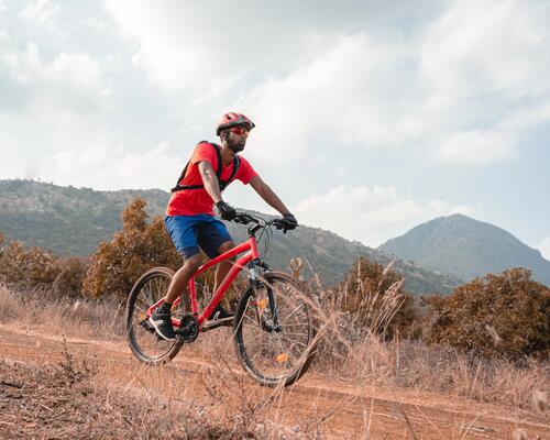 Mężczyzna w kasku w okularach z plecakiem na plecach jadący rowerem w terenie