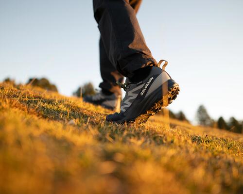 Une femme qui attache ses chaussures de randonnée assise sur une roche