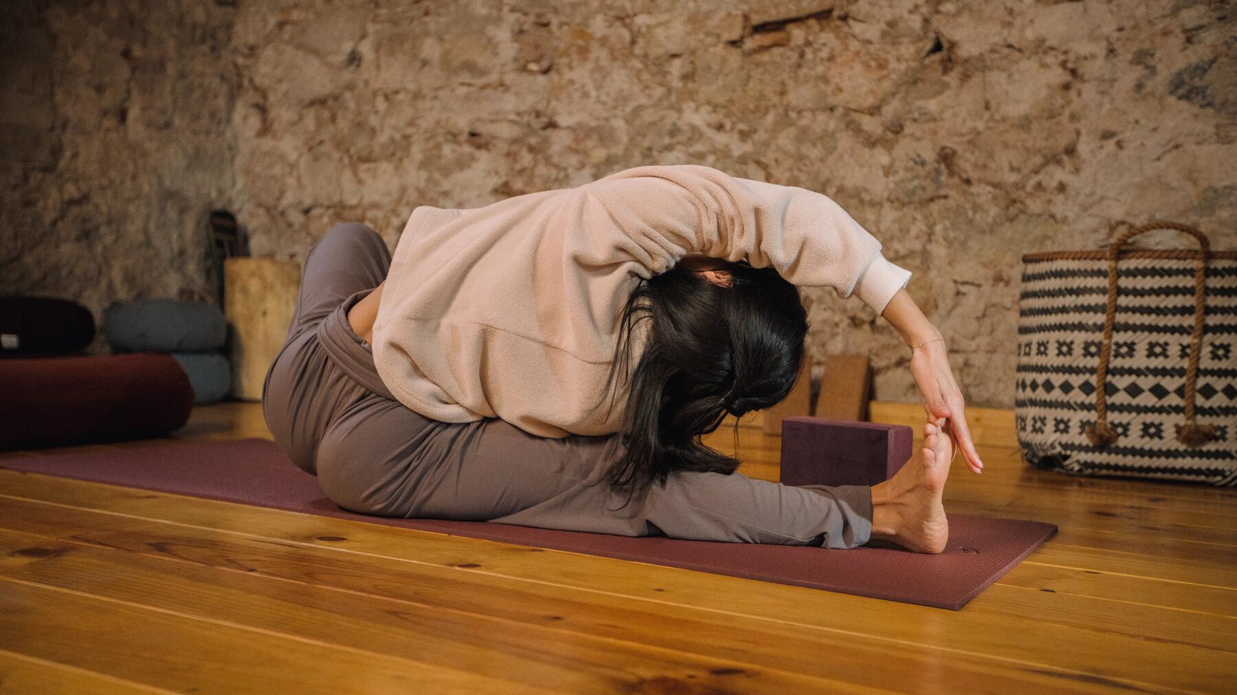 Frau führt eine dynamische Hormonyoga-Übung mit fokussierter Atmung auf einer Matte aus