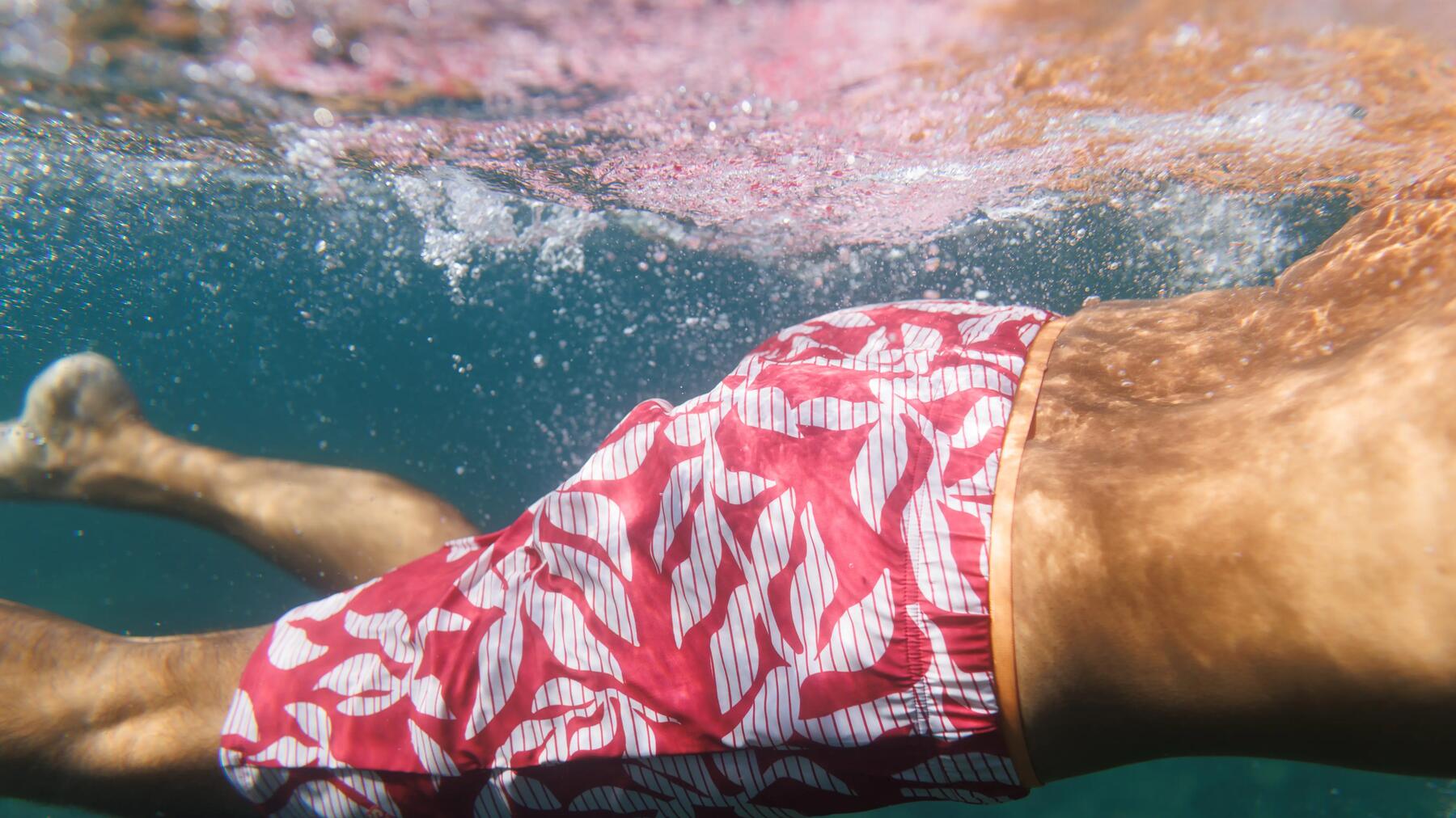 Mann schwimmt in rot weißer Badehose für Herren