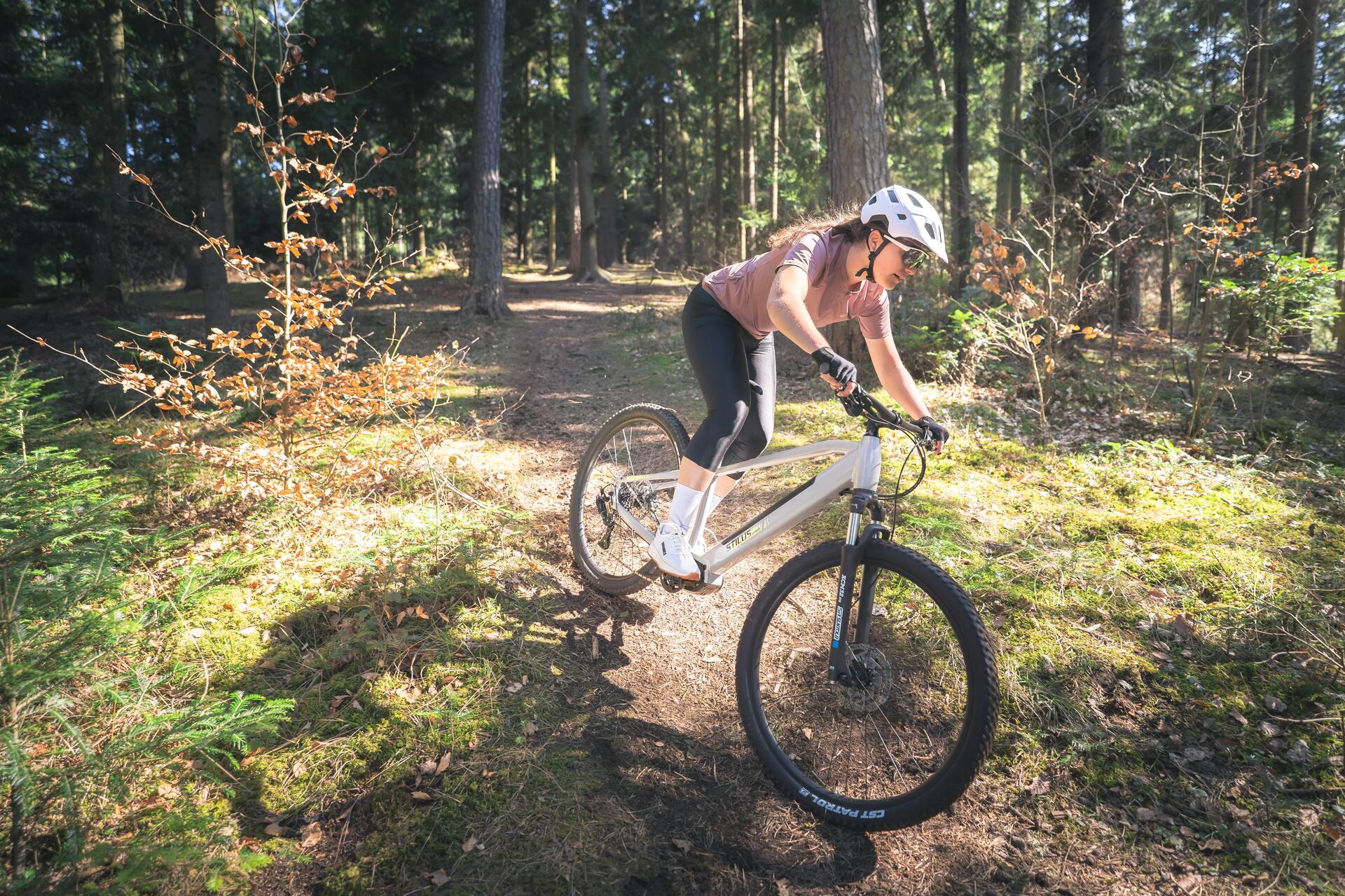 Kobieta w kasku rowerowym jadąca na rowerze w lesie