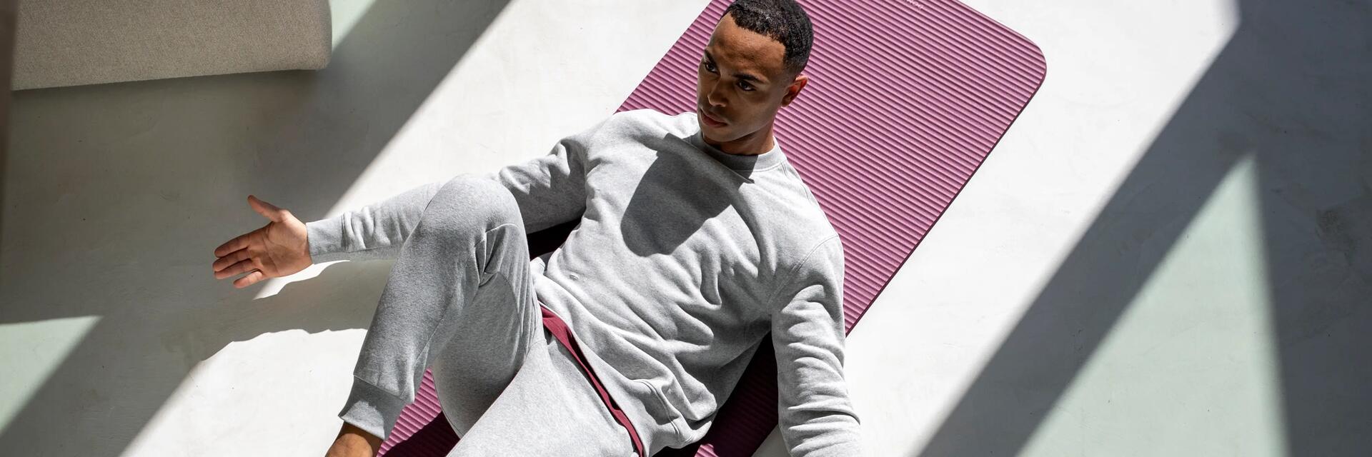 Mężczyzna ćwiczący pilates na macie w domu