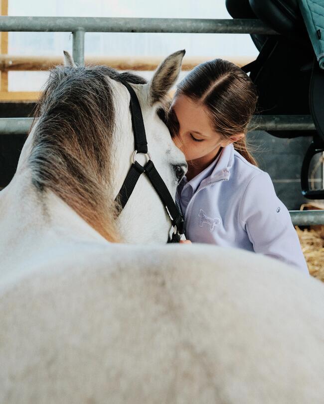 Kind auf dem Rücken von einem Pony, lehnt sich vorne auf den Hals