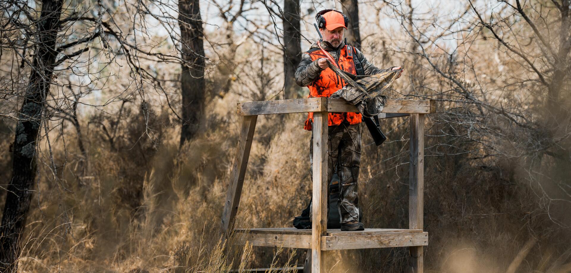 Un chasseur en battue sur un mirador se préparant au lancement de la chasse et qui portent un gilet fluo