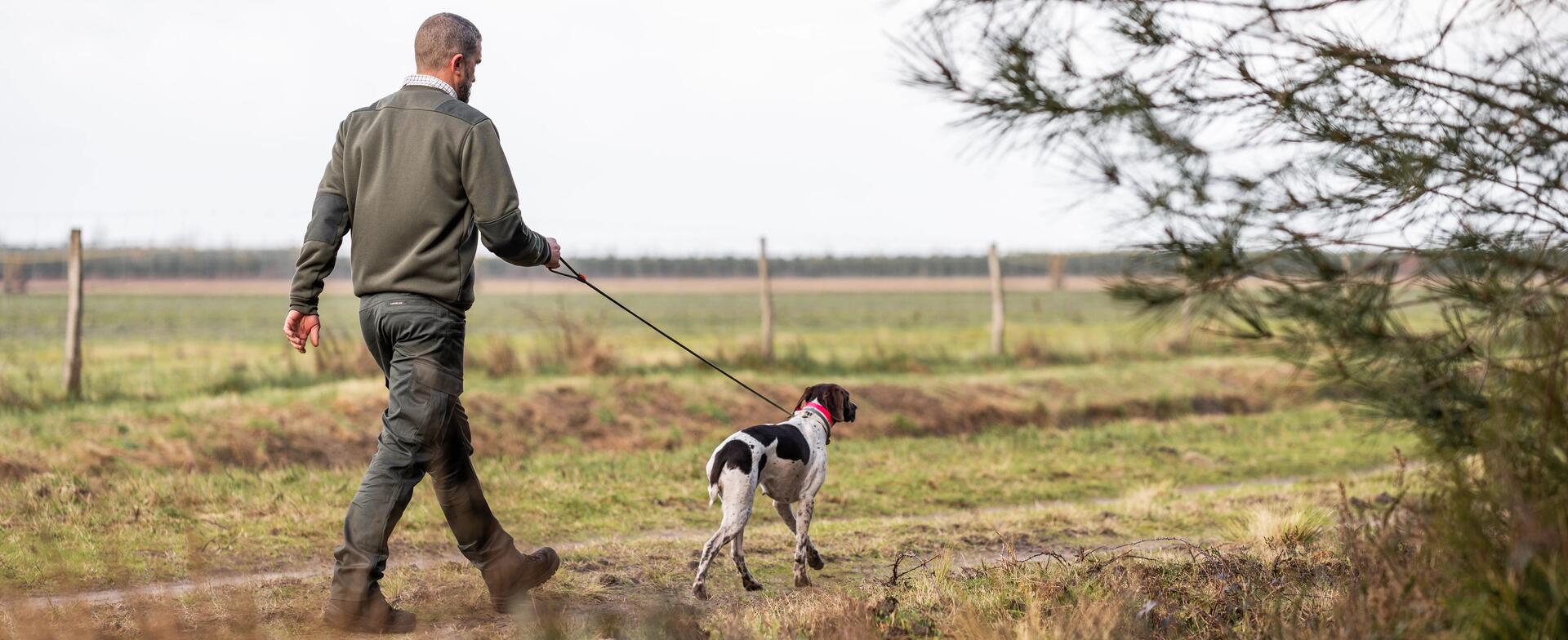 Un chasseur qui repère son territoire avec son chien se promenant sur un chemin 