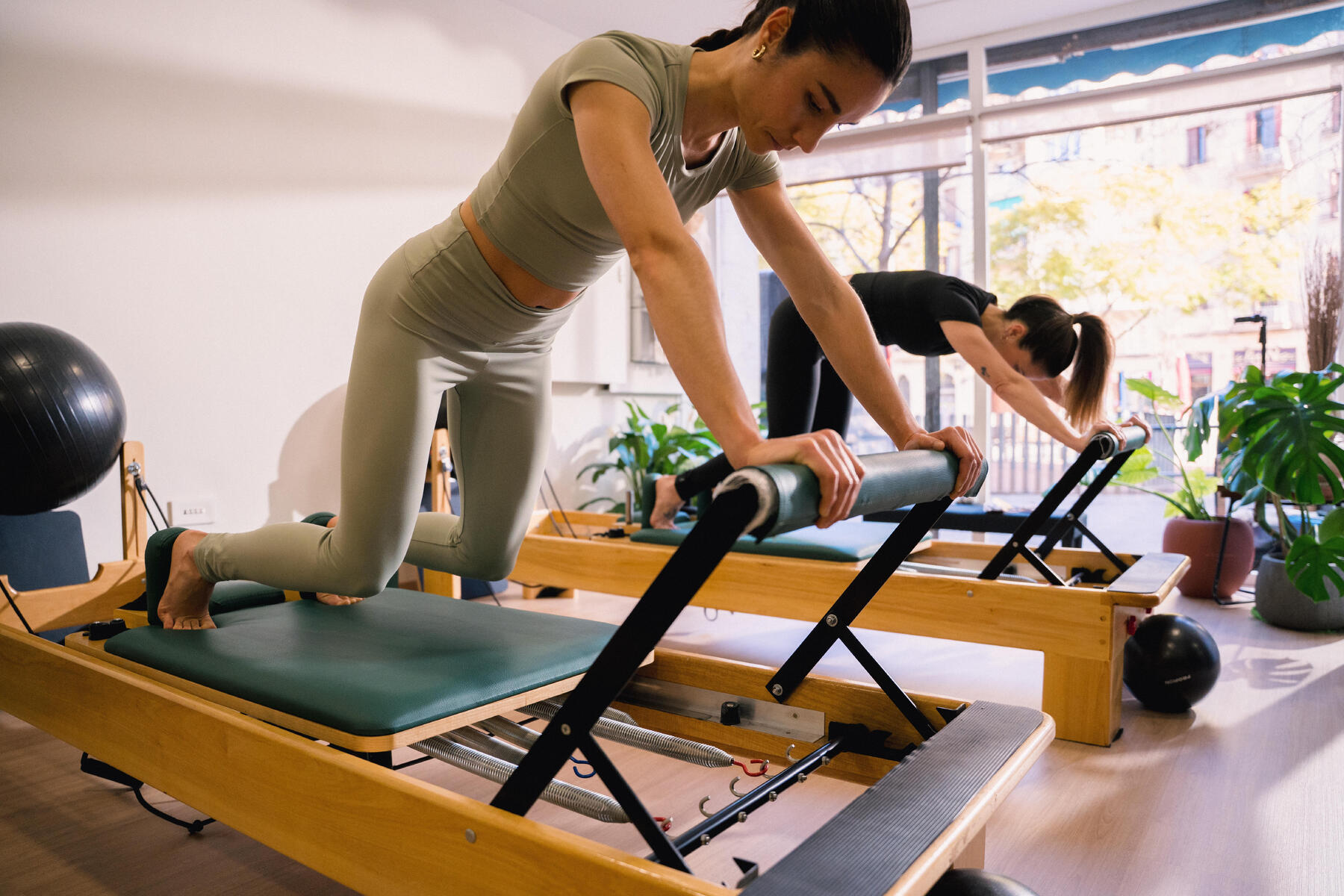 Kobiety w odzieży do pilatesu trenujące pilates na reformerach