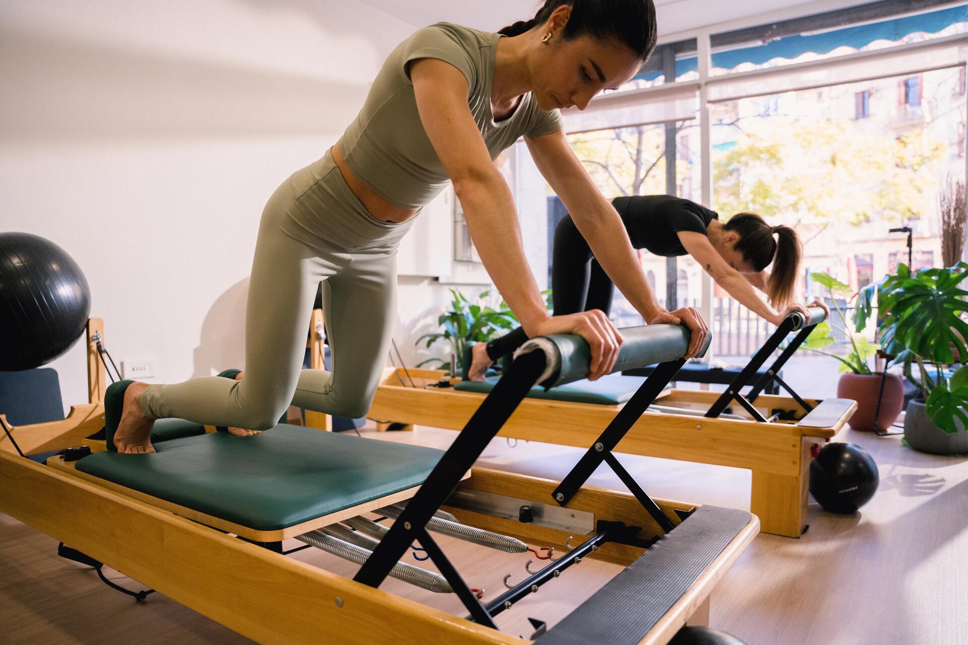 Kobiety w odzieży sportowej ćwiczące na reformerach