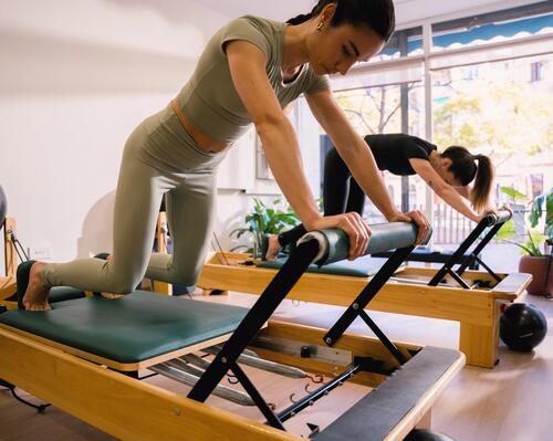 Kobiety w odzieży do pilatesu trenujące pilates na reformerach