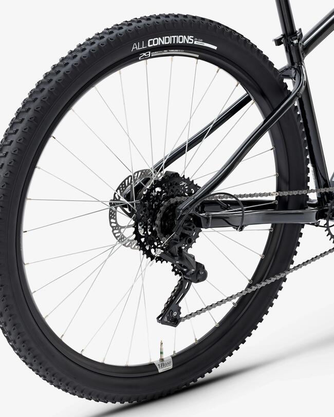 Mann mit schwarzem Helm fährt auf schwarzem geländegängigen Fahrrad einen steilen Waldweg hinauf