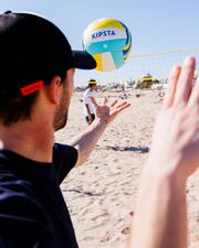 Pessoa com um chapéu de sol numa praia a jogar voleibol de praia