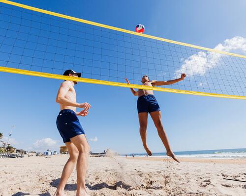 Zwei Freunde spielen Beach Volleyball und halten sich an die Regeln