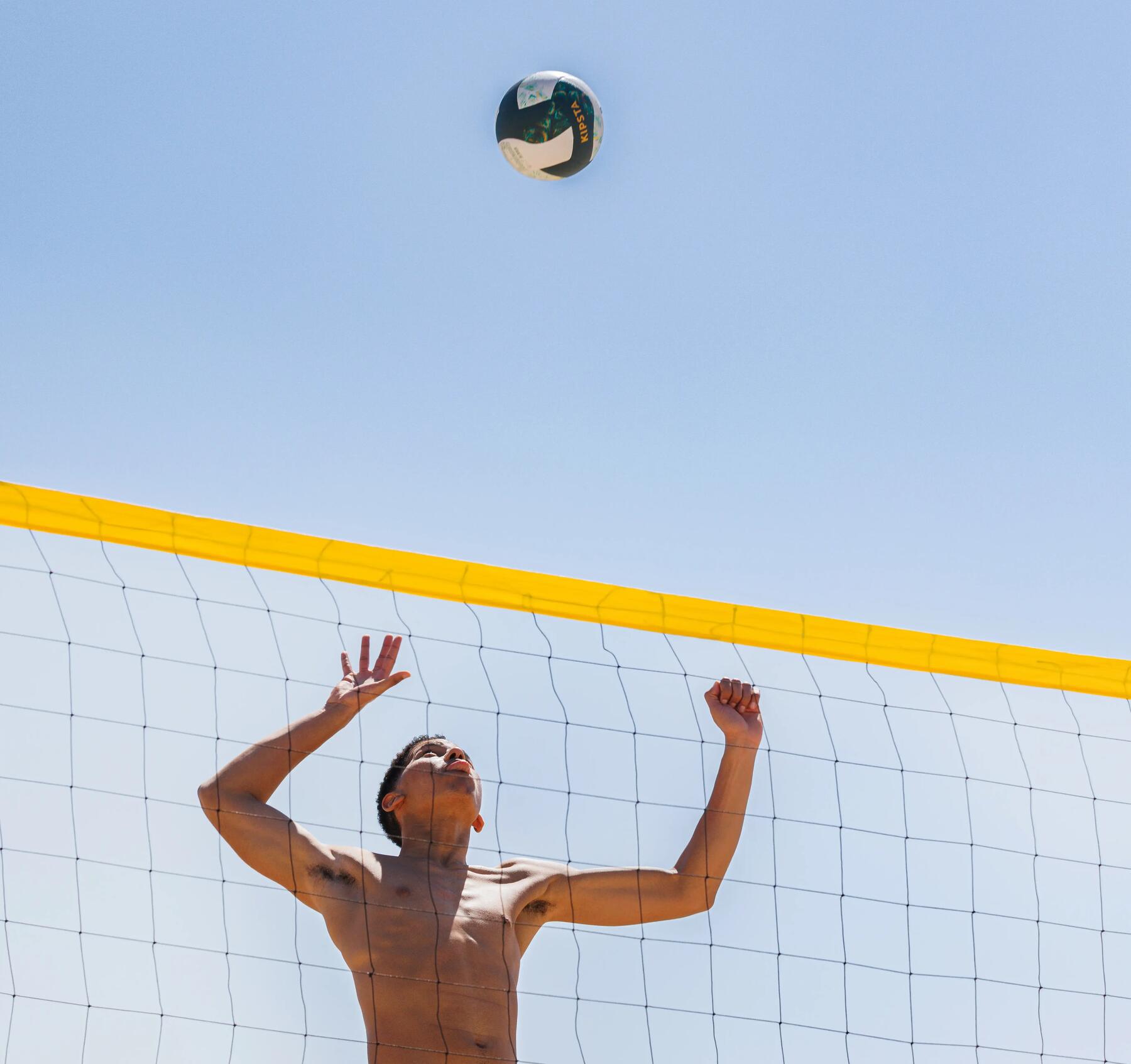 Ein Mann schlägt am Beachvolleyballnetz