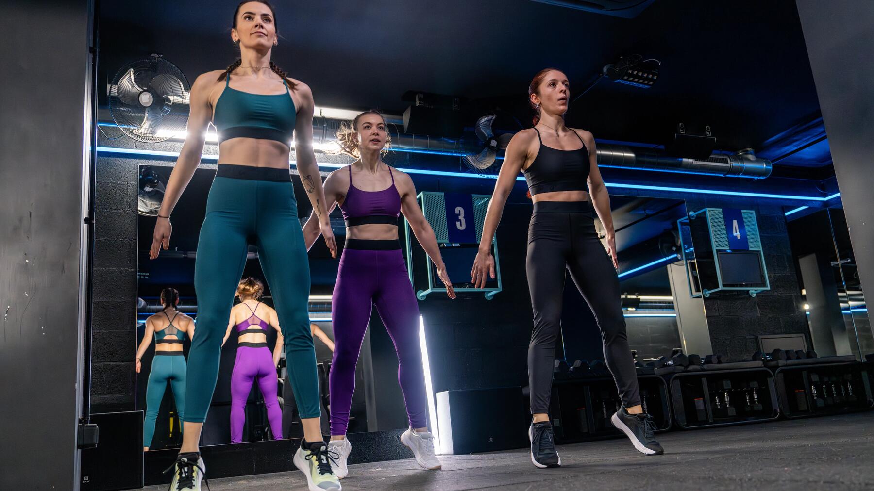 Gruppe von Frauen in dunklem Fitnessraum beim Bein-Workout