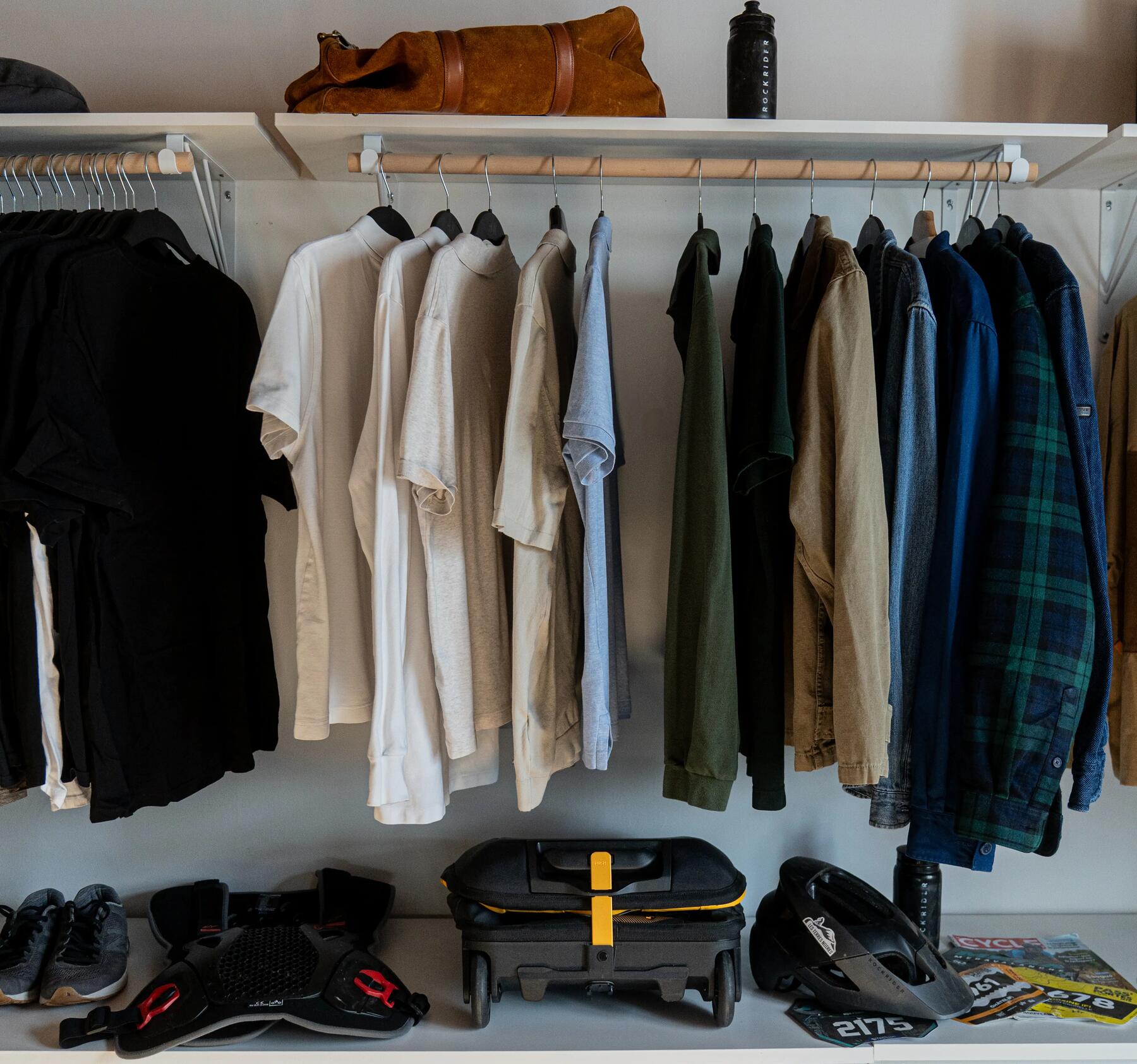 Ein Handgepäck liegt in der Garderobe unter Jacken