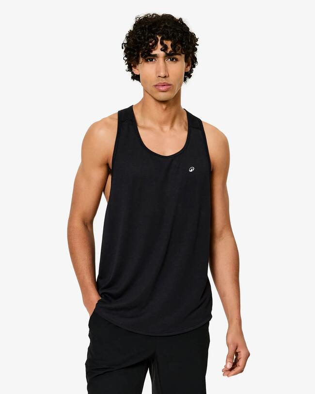 Junger Mann mit lockigem Haar in schwarzem, ärmellosem Tanktop und Sporthose.