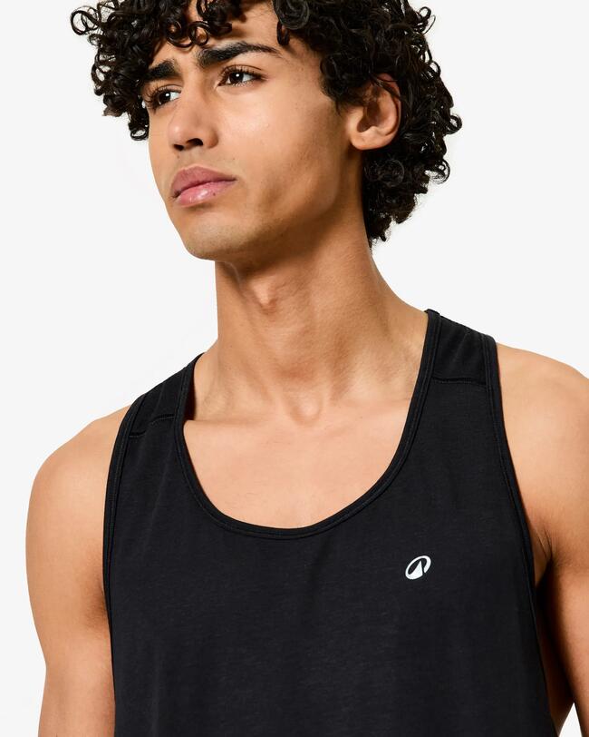Nahaufnahme des Oberkörpers eines Mannes mit lockigem Haar in schwarzem Tanktop.