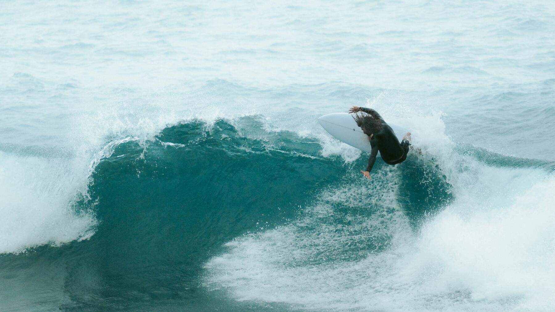 woman walking on a beach to reach the water with her surf board