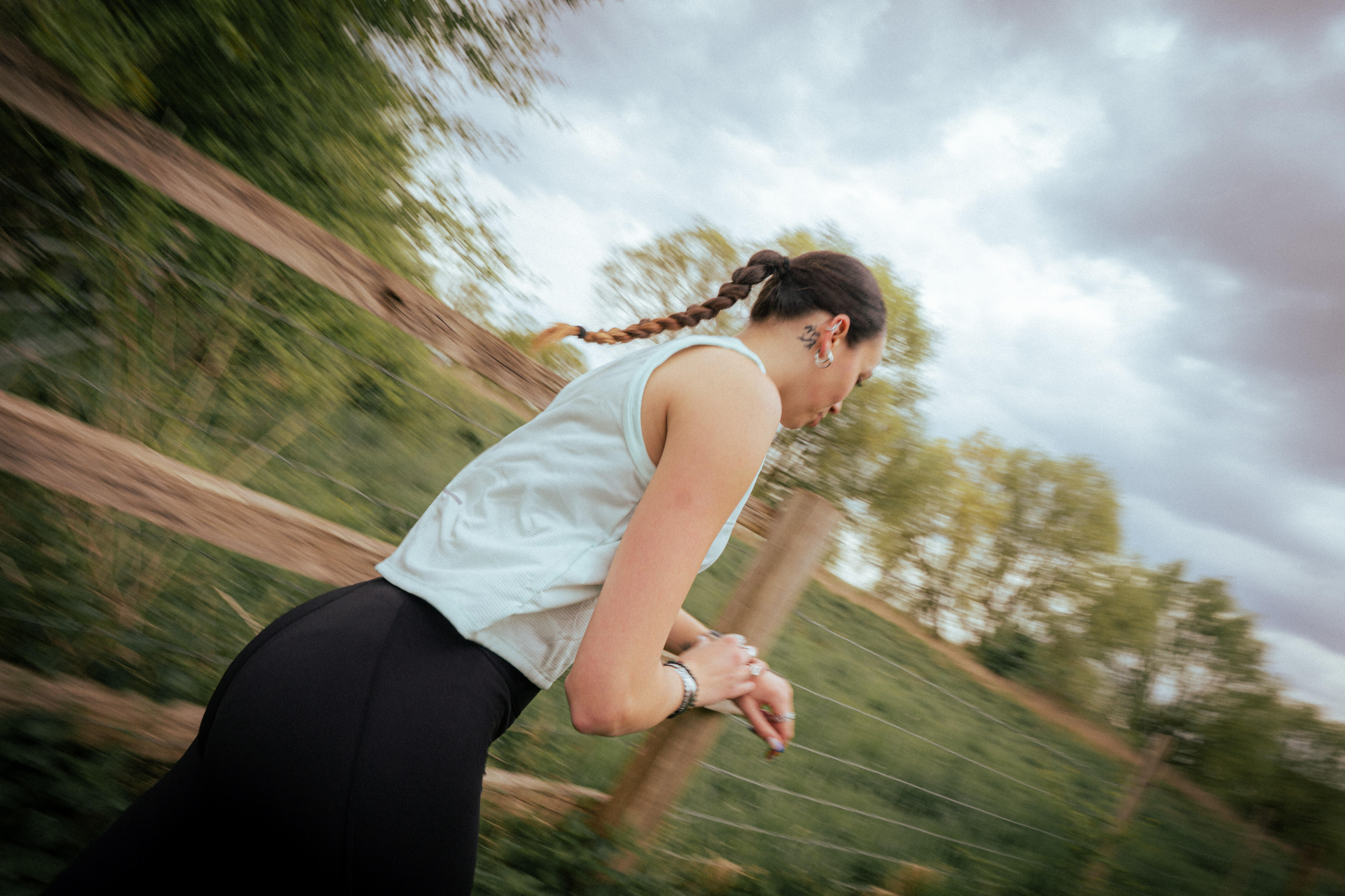 Woman running beside a wooden fence while wearing a step counter watch