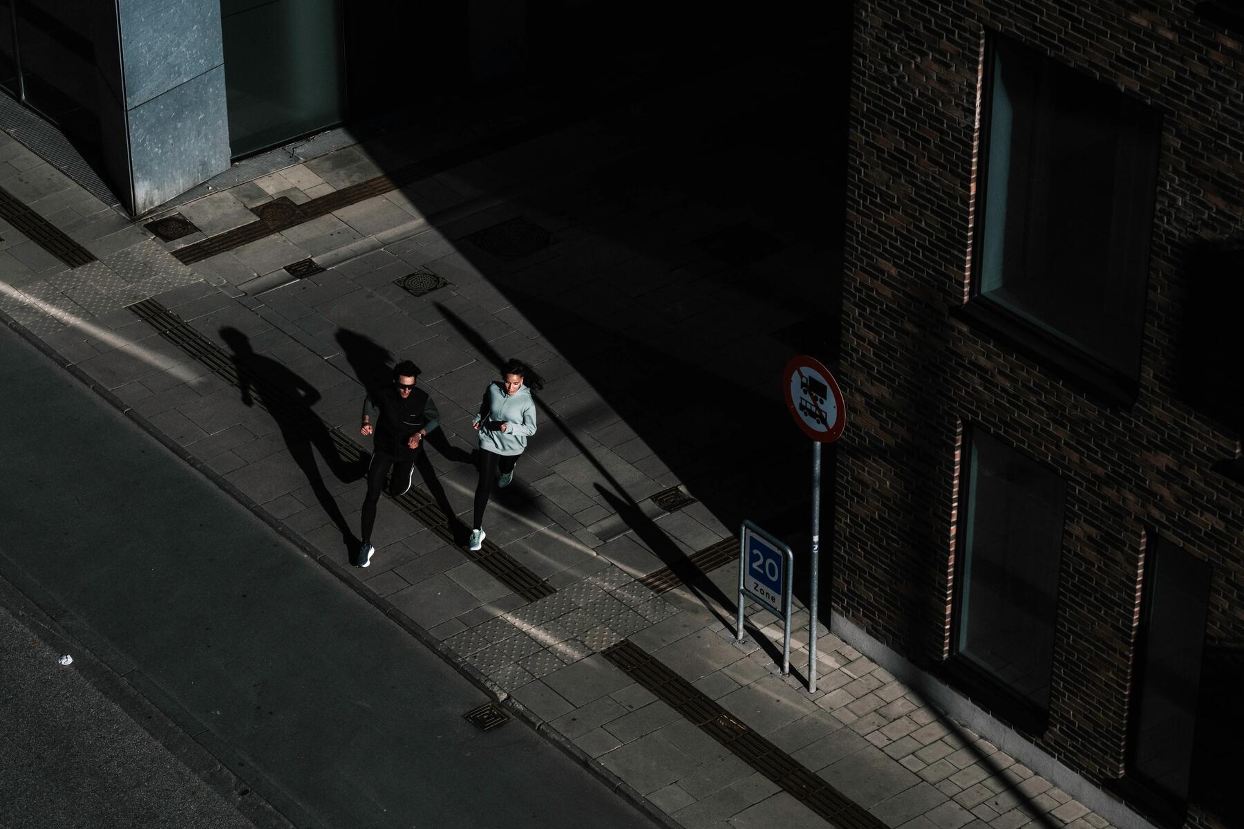 Man en vrouw samen aan het hardlopen over de weg