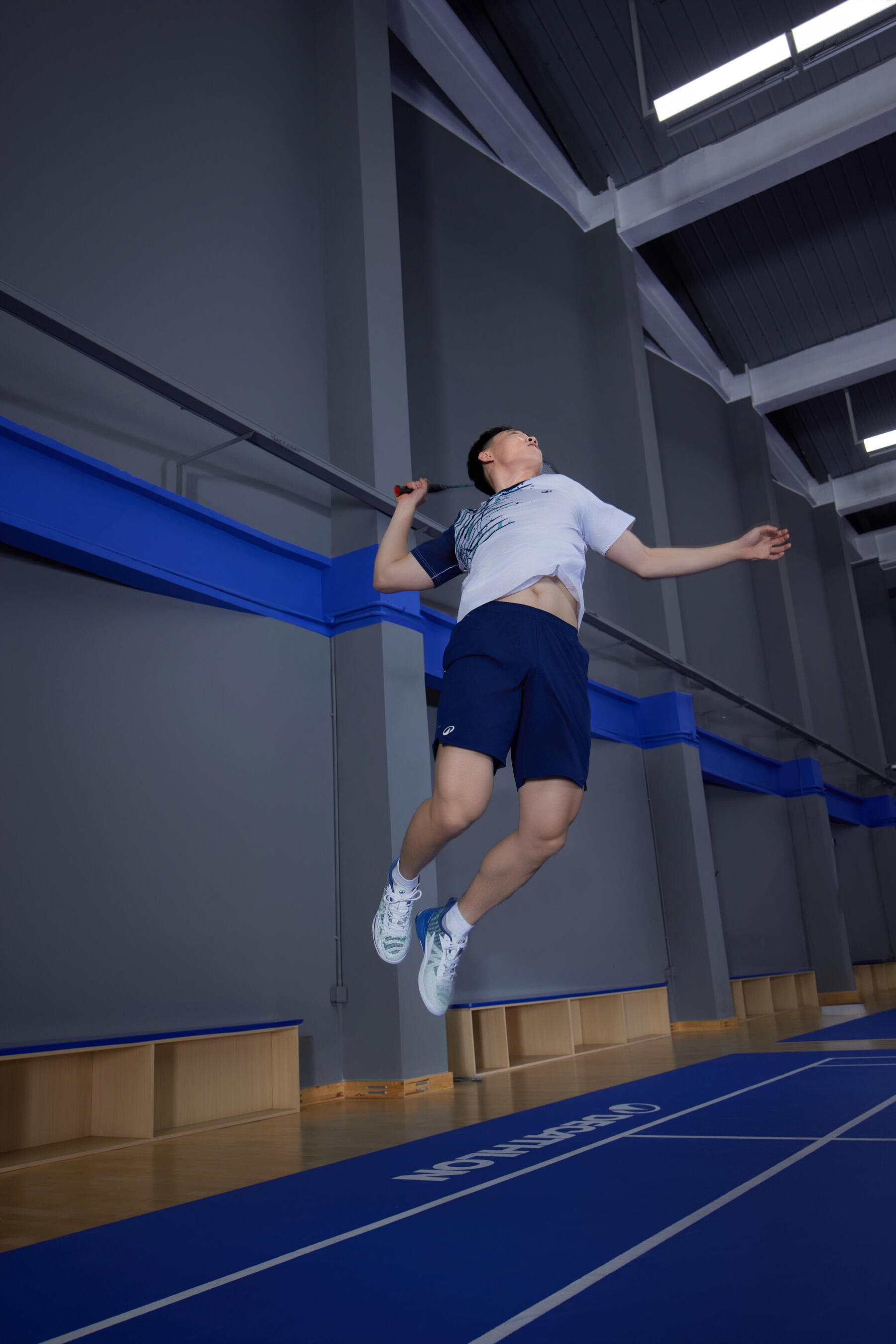 Mann schmettert beim Badminton in einer Sporthalle