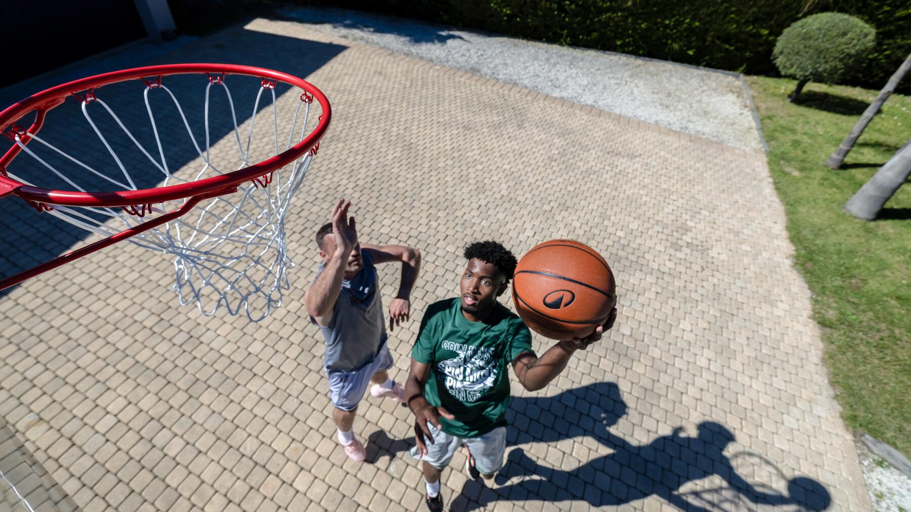 Zwei Männer spielen Basketball. Gezeigt aus der Vogelperspektive mit Korb links.