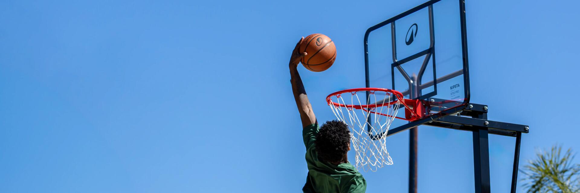 Zwei Männer spielen Basketball vor der Garage.