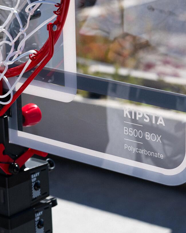 Roter Basketballkorb, weißes Netz, blauer Himmel, Szenerie mit klaren Linien und sportlichem Flair.