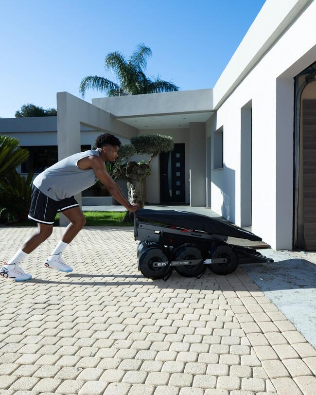 Basketballkorb mit Ständer, klappbar und mobil, schwarz, rollbar, vor modernem Gebäude auf gepflasterter Fläche.