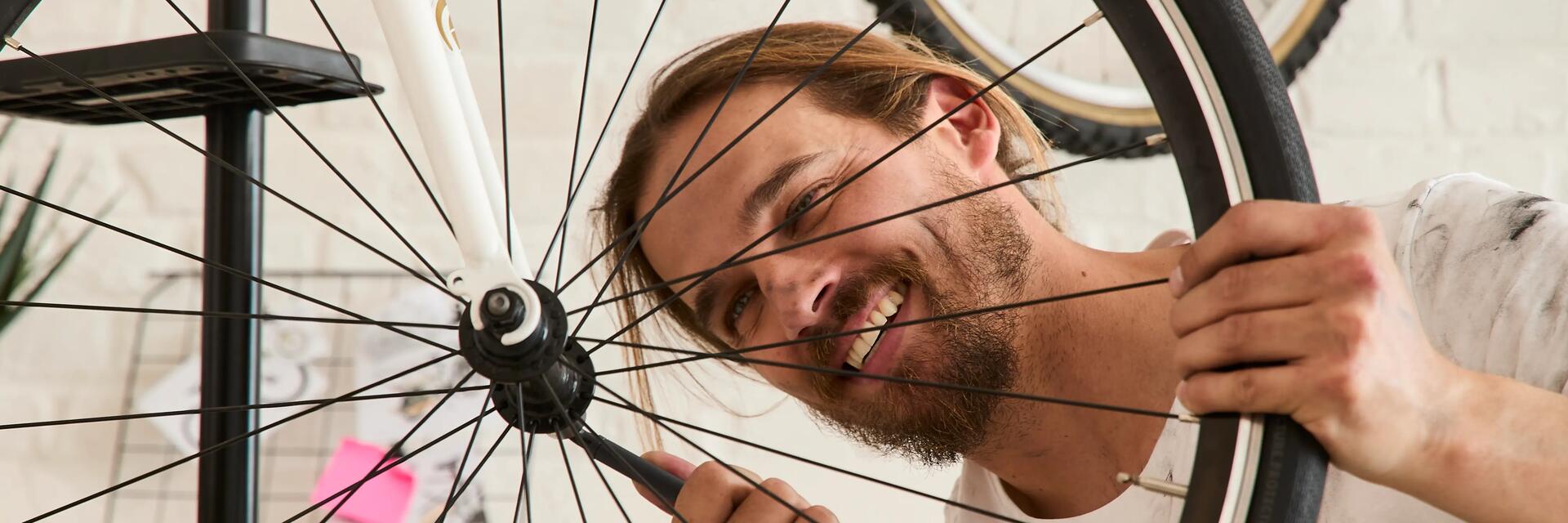 Mężczyzna dokręcający kluczem piastę rowerową w kole