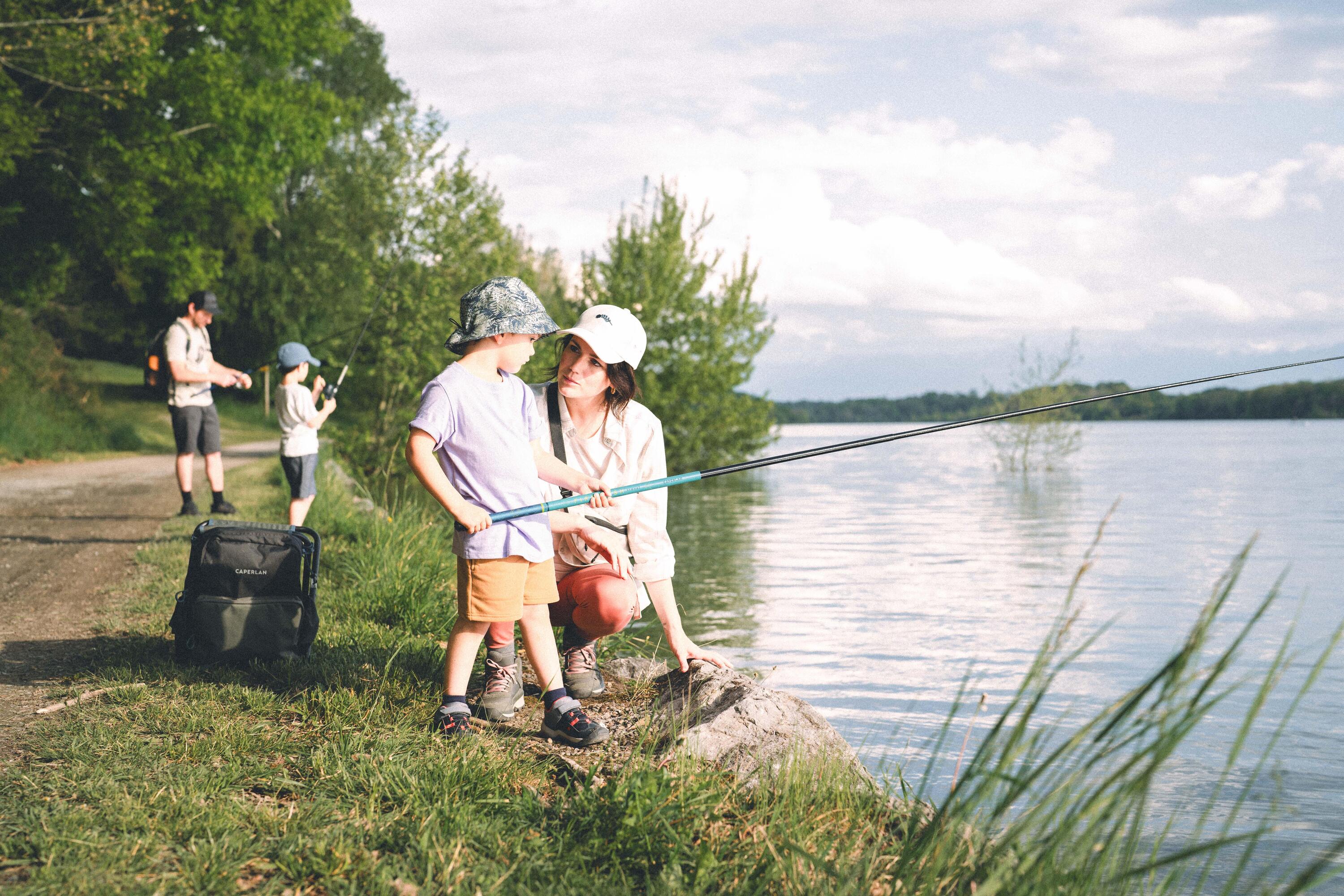 EIn Kind macht gerade seine ersten Angelerfahrungen am Wasser. Die Mutter kniet nebendran und hilft