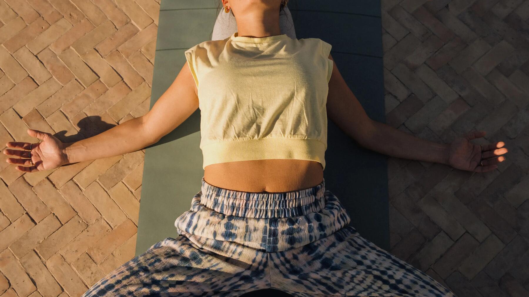 Frau führt entspannte Yoga Asana auf Yogamatte draußen aus