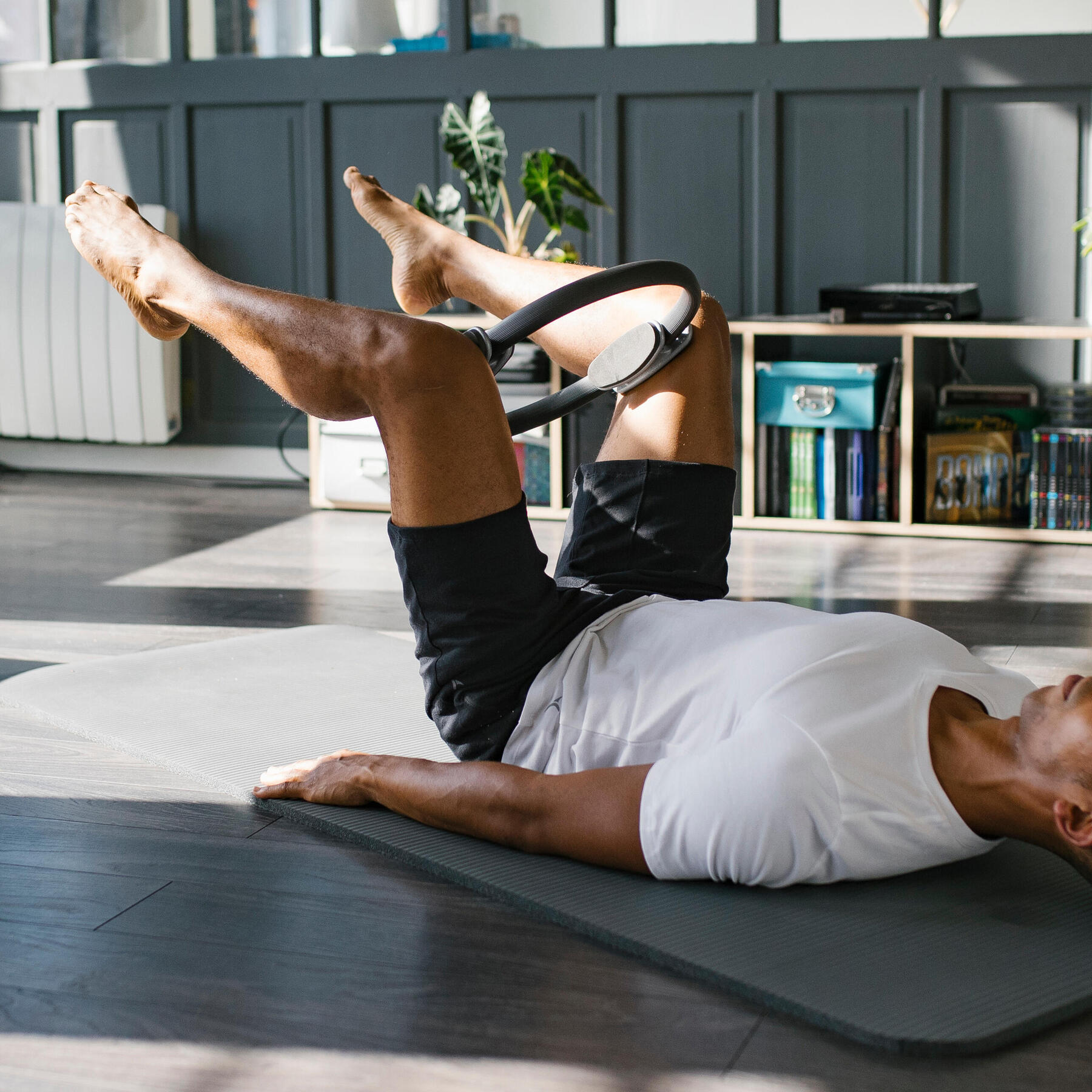 Mężczyzna leżący na macie ćwiczący nogi z obręczą do pilatesu