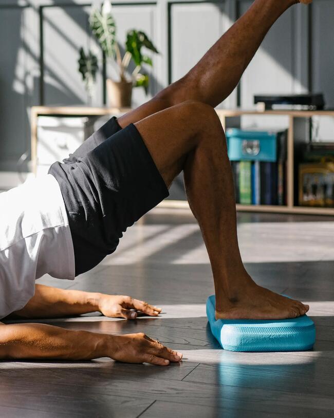Ein Mann macht Übungen auf einem Balance-Pad.