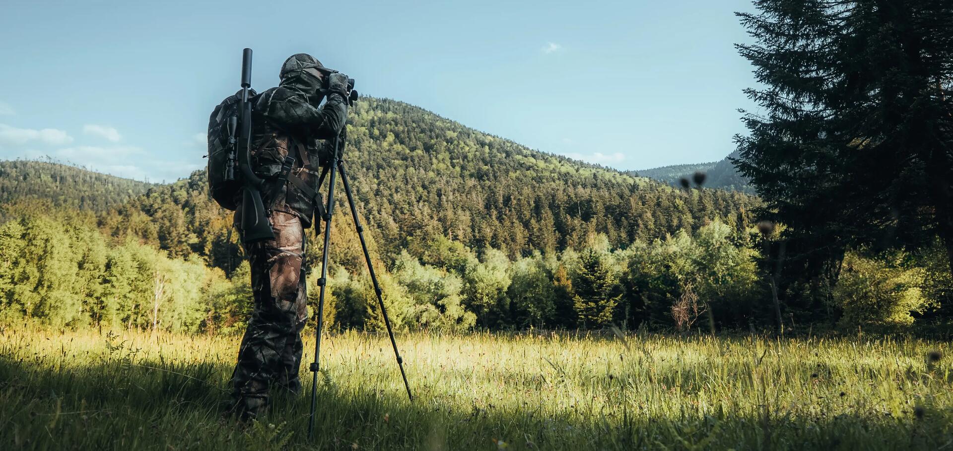 Un chasseur qui observe aux jumelles avec une canne de pirsch