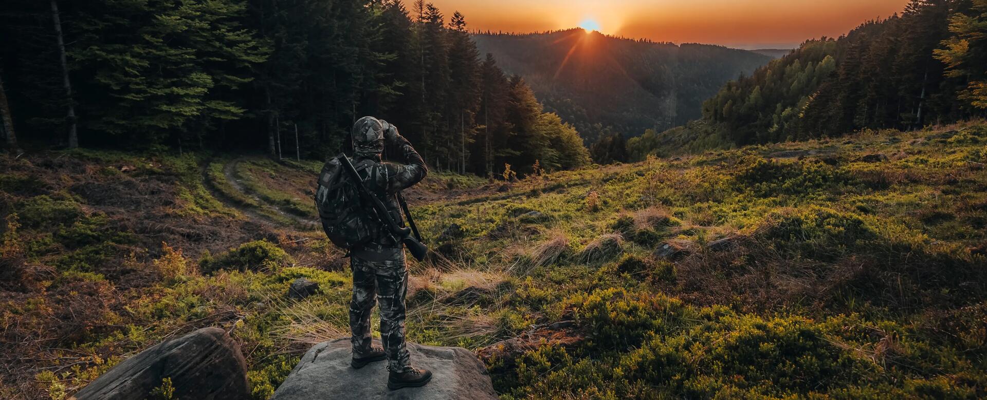 Un chasseur à l'approche qui observe son environnement avec les jumelles HTR Solognac