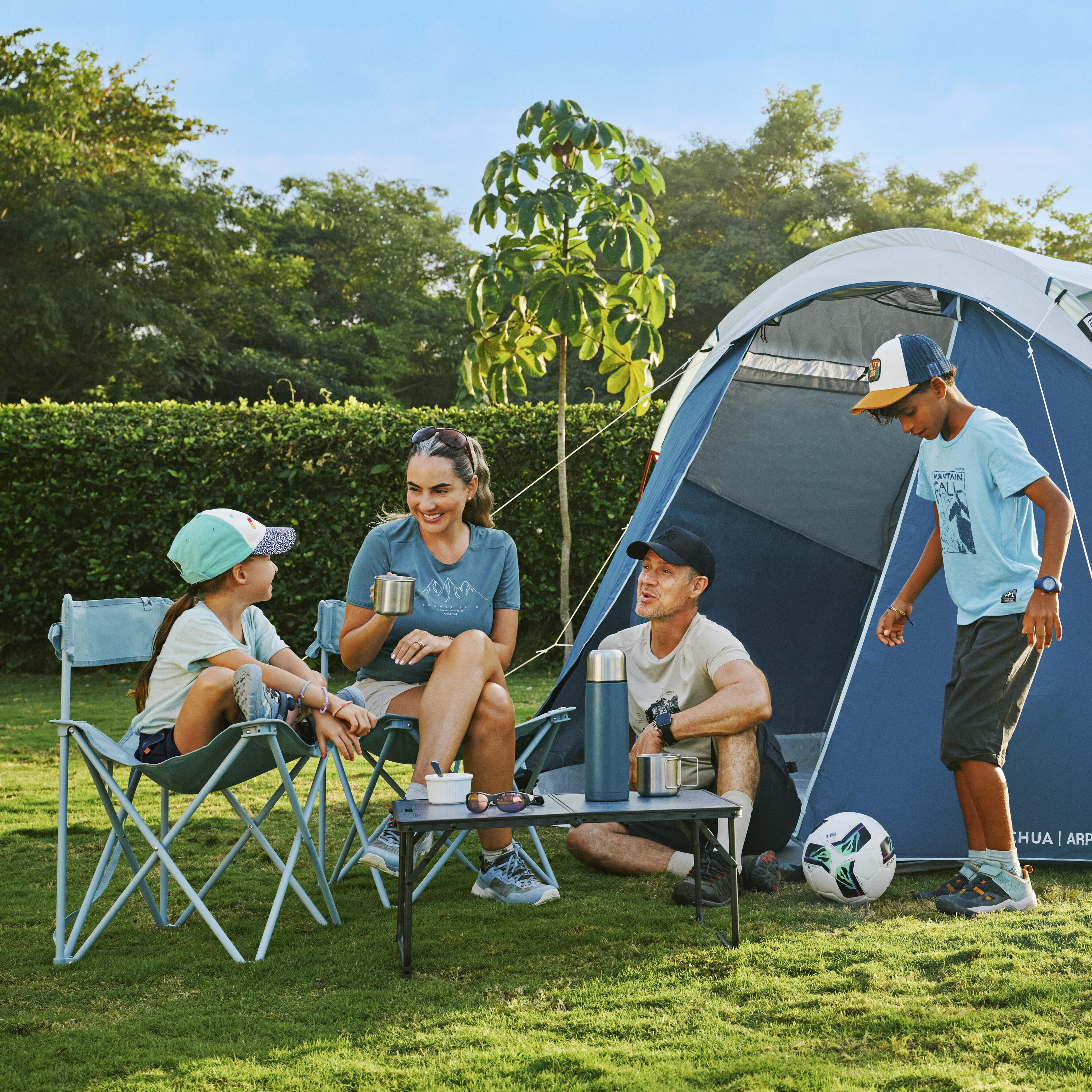 A family sitting on camping chairs infront of a tent