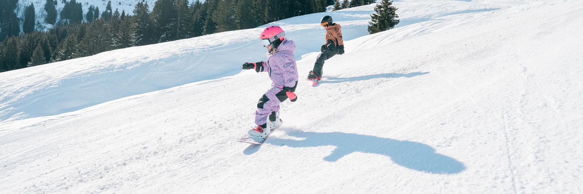 Kobieta i mężczyzna w kasku i w goglach jeżdżący na snowboardzie
