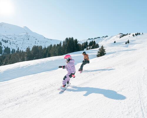 Kobieta i mężczyzna w kasku i w goglach jeżdżący na snowboardzie