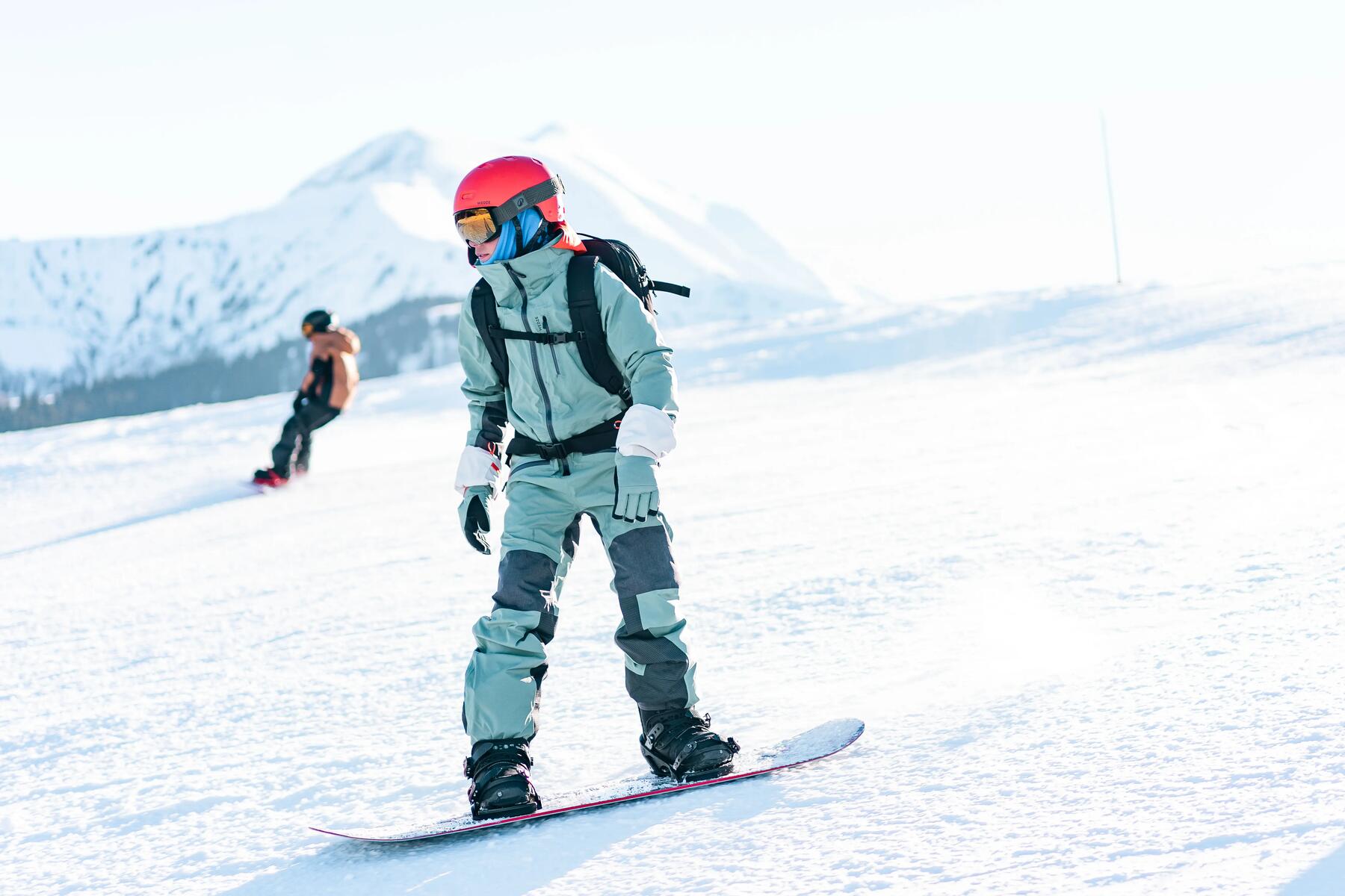 Dwie osoby w kasku i w goglach jeżdżące na snowboardzie