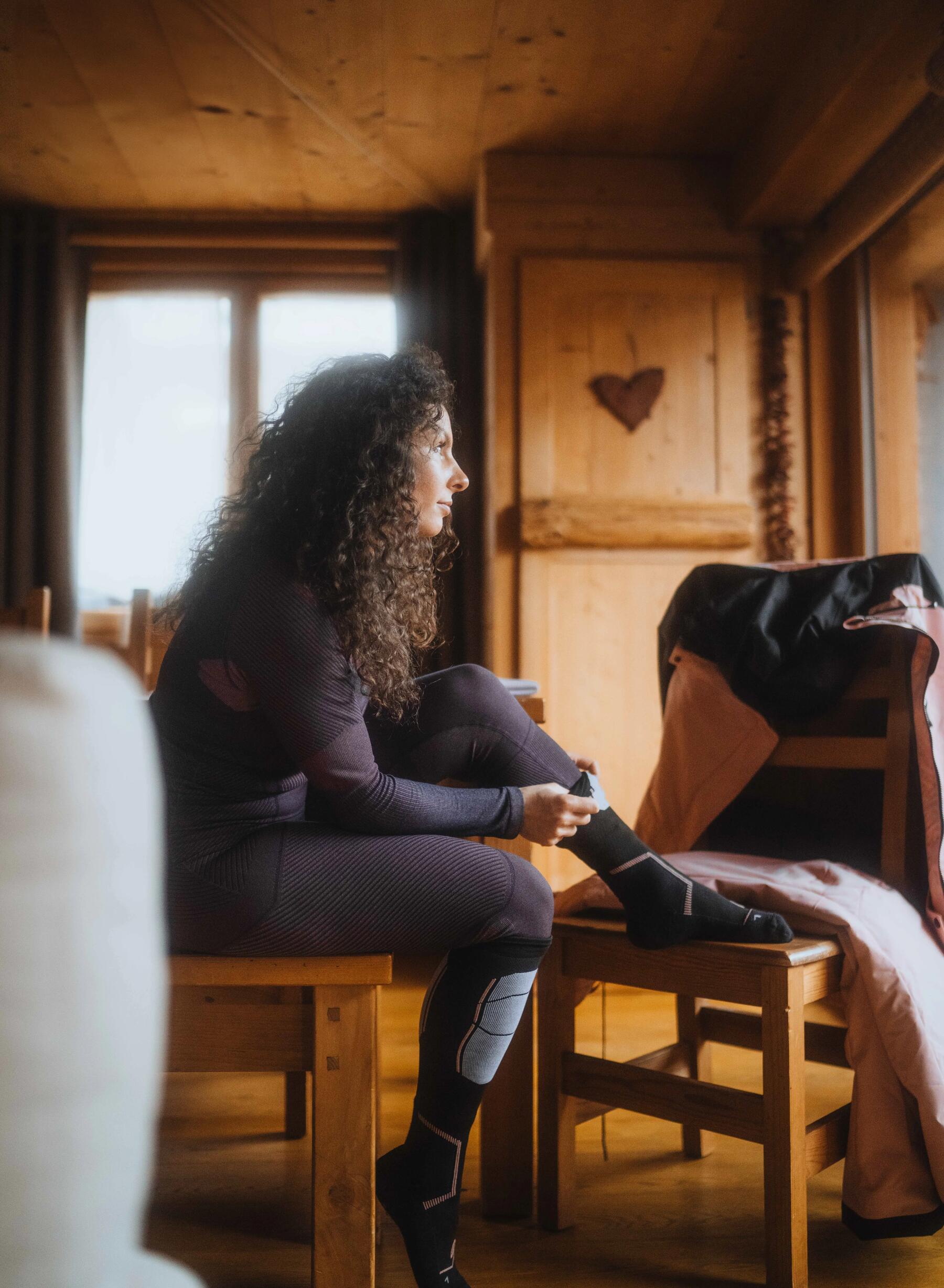 Woman putting on a Decathlon Quechua ski sock.