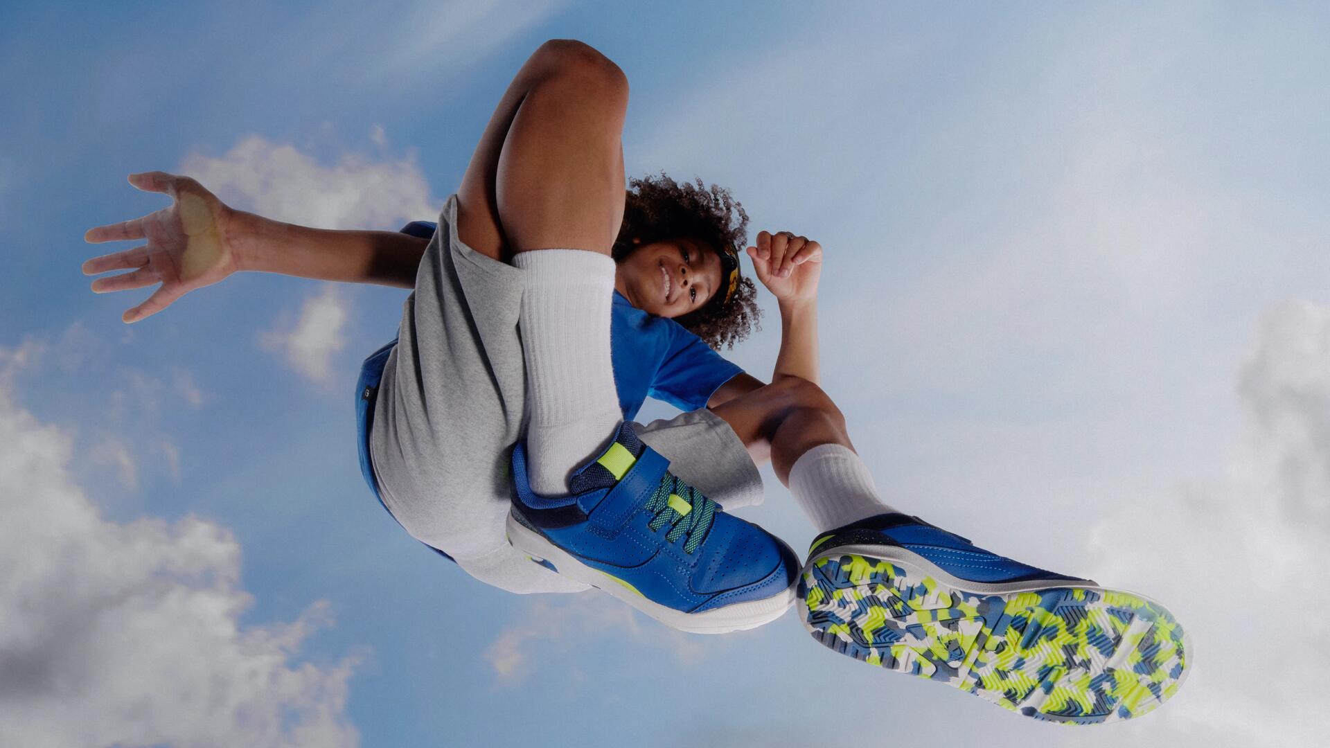 Foto van een kind langs uit beneden perspectief. Het kind draagt een sportieve outfit met sportschoenen met velcro.