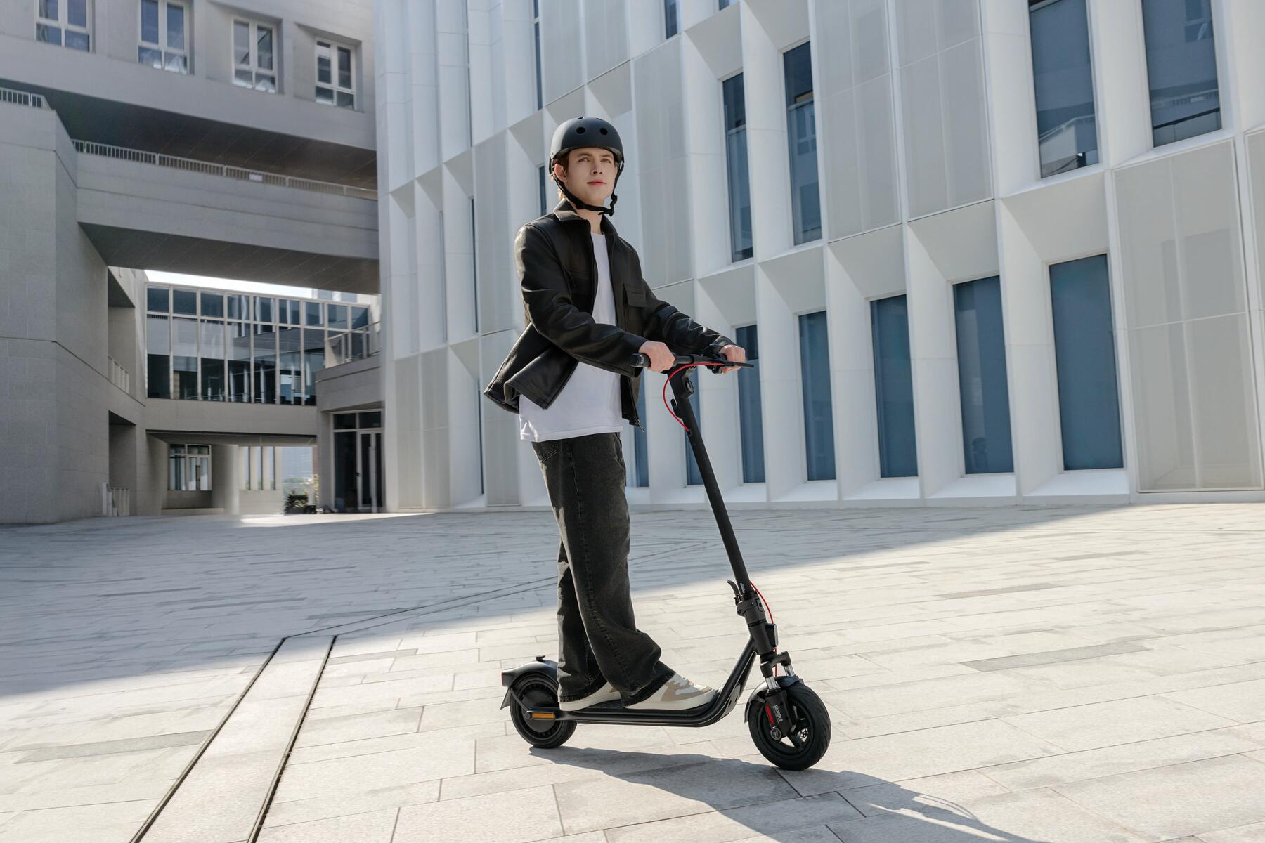 Mężczyzna w kasku jadący na hulajnodze elektrycznej