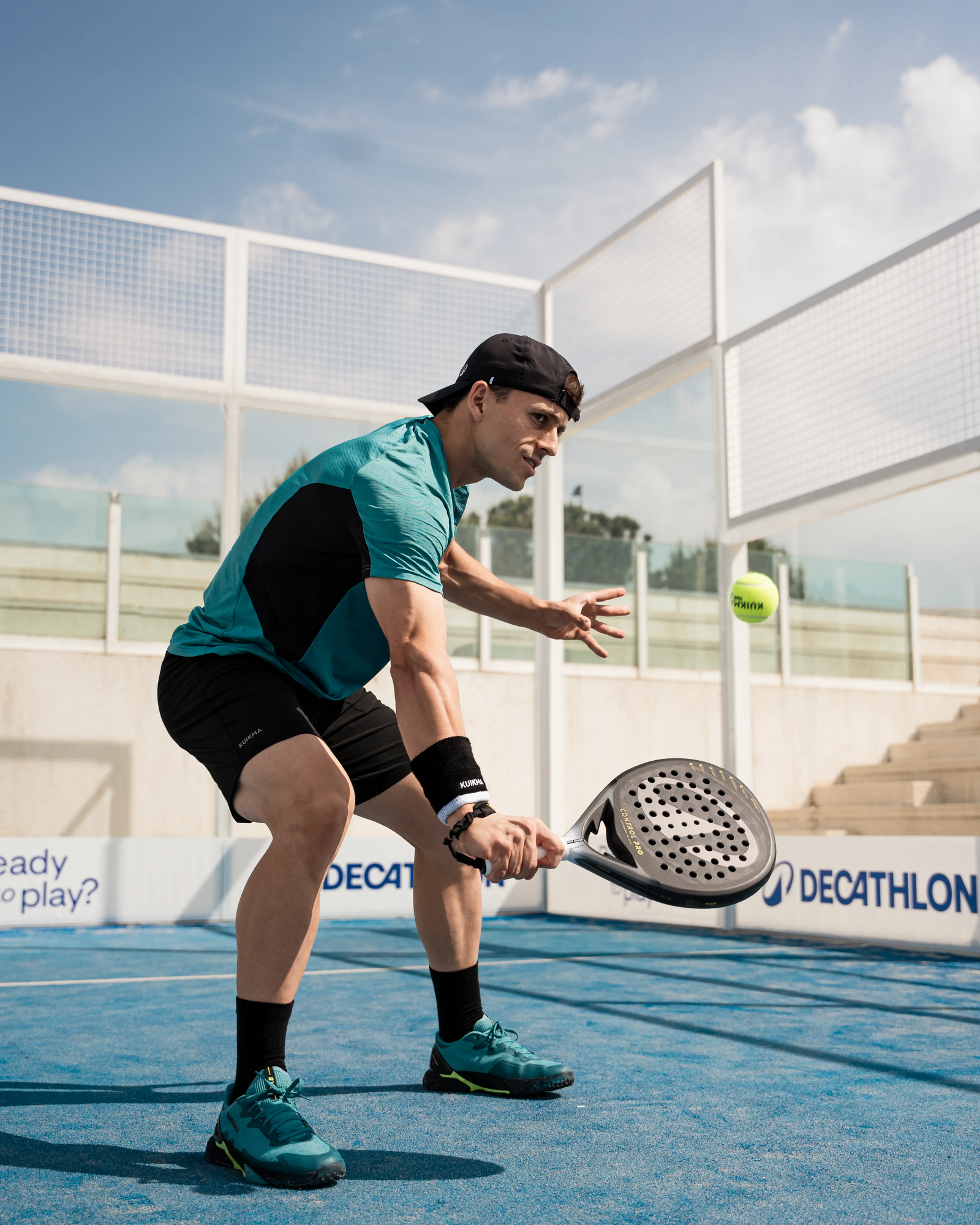 Ein Mann in Sportkleidung hält einen Padel-Schläger und einen Ball in der Hand, bereit zum Spielen.