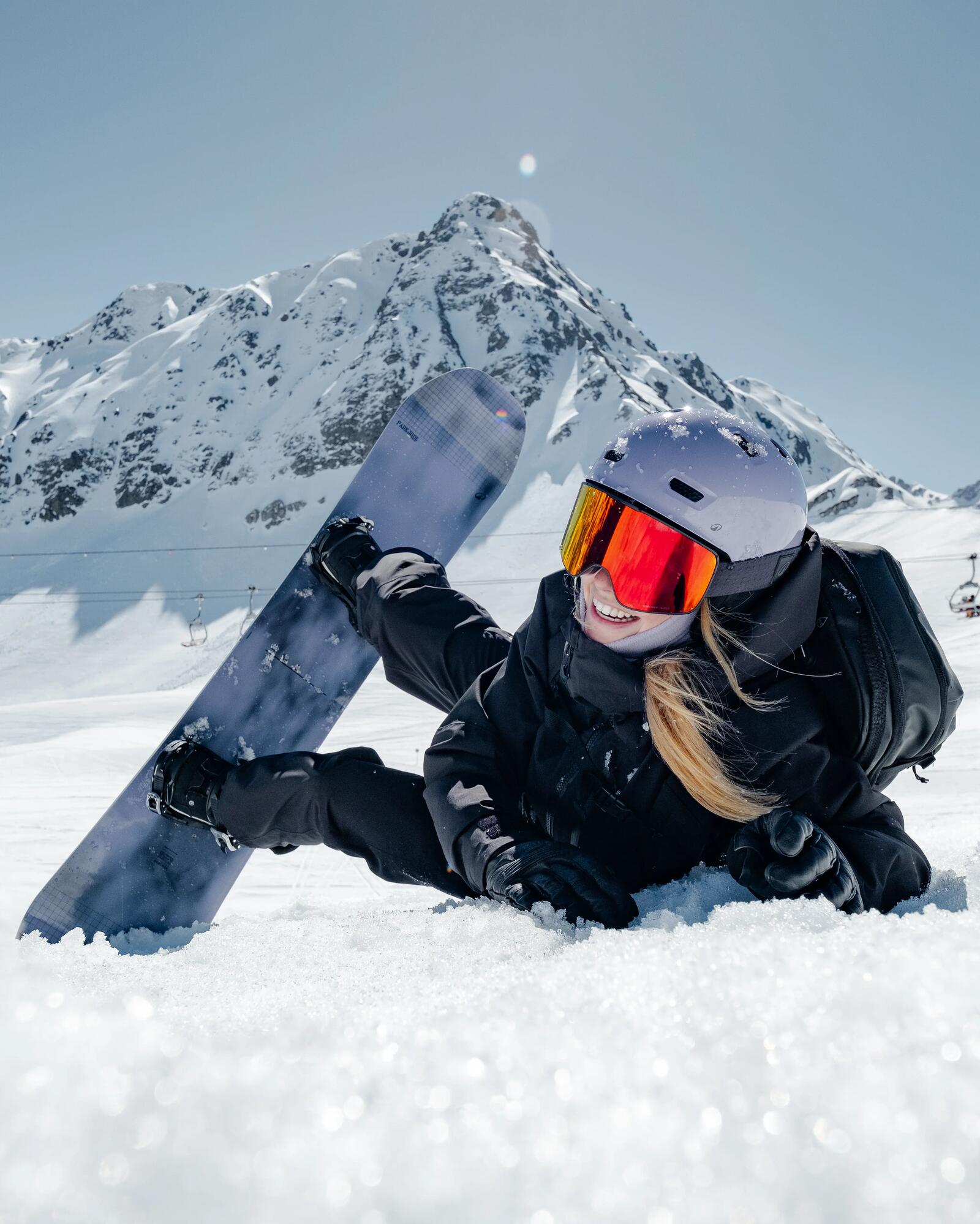 Snowboarderin liegt im Schnee.
