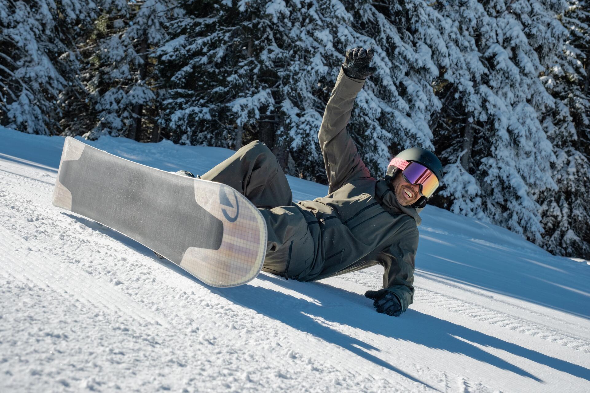 Mężczyzna w kasku snowboardowym leżący na stoku po upadku