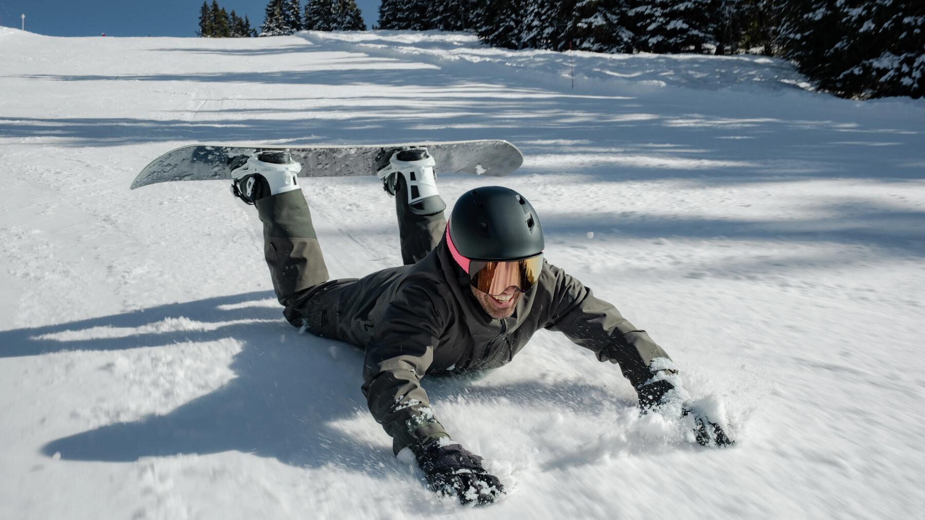 Mężczyzna leżący na śniegu z przypiętą deską snowboardową
